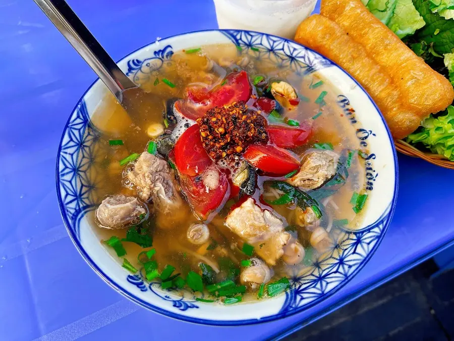 Bát bún ốc nóng hổi, màu nước dùng trong veo, điểm xuyết cà chua đỏ và tía tô xanh.