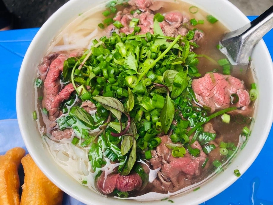 Tô phở bò với nước dùng trong, bánh phở mềm dai, hành hoa xanh mướt.