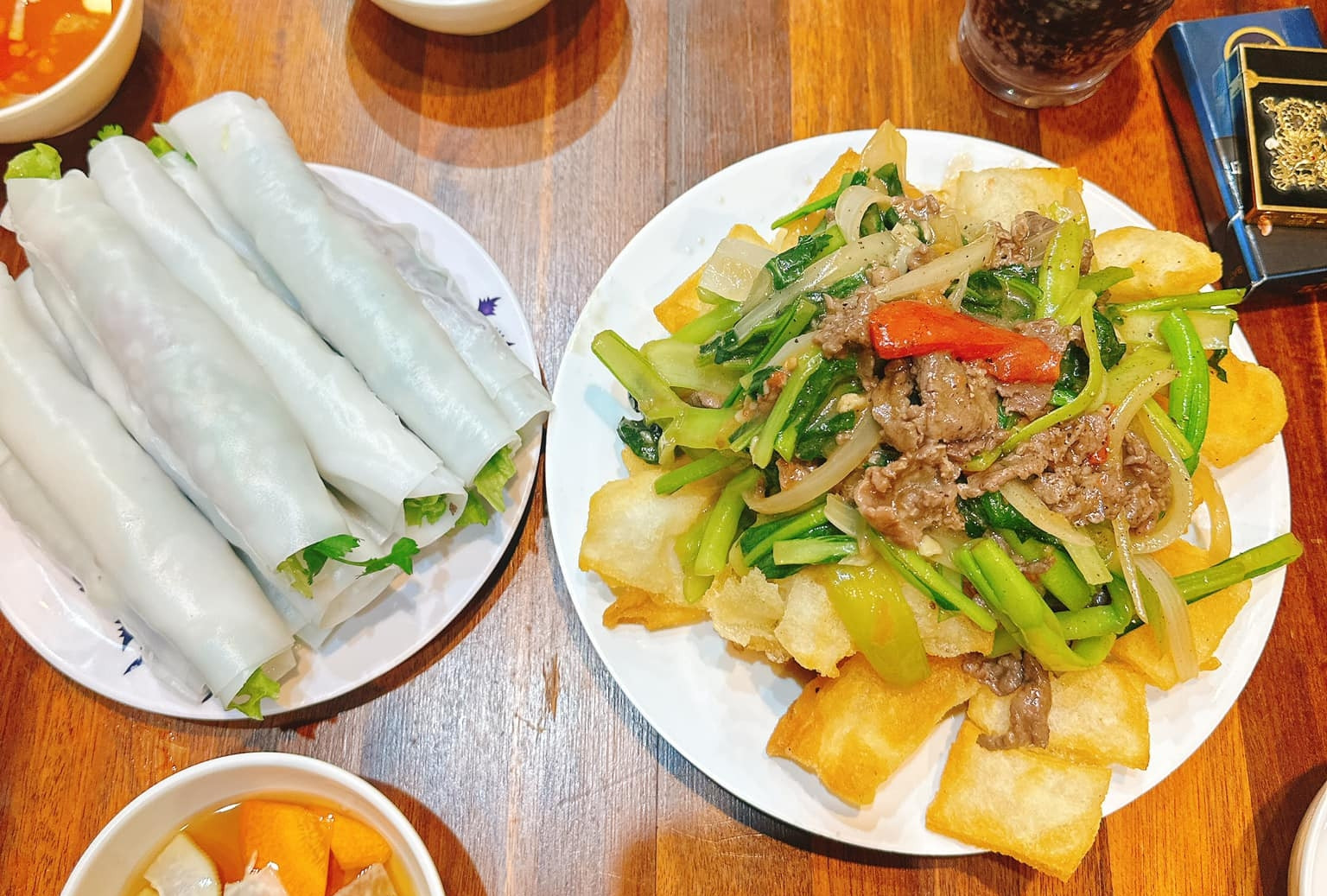 Cuốn phở trắng mềm, ôm lấy thịt bò xào và rau sống.